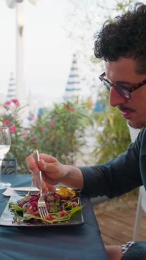 Sahilde öğle yemeği yerken deniz manzarasına hayran olan bir adam. . 