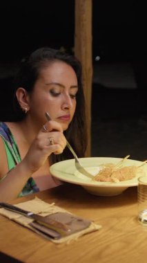 Otelin sıcacık ışığı altında bir gurme yemeğinin tadını çıkaran bir kadın. .