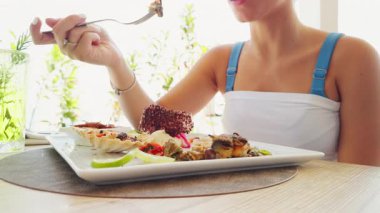 Yazın deniz kenarında lüks bir restoranda balık yiyen genç bir kadın..