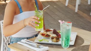 Genç Kadın Deniz kenarındaki sahilde taze bir kokteyl içiyor..