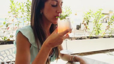 Kız, yaz tatilinde deniz kenarındaki bir barda taze bir kokteyl içiyor..