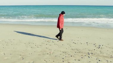 Deniz kıyısındaki bir kış yürüyüşünde Taşları Toplayan Adam. 