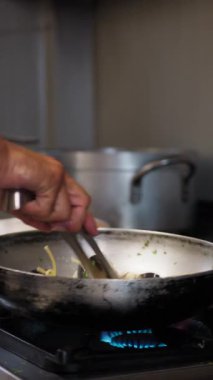 Şef, tavada midye ile maşa pişiriyor. . 