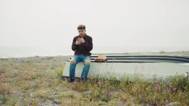 Adam kışın sahilde bir teknede oturur ve dua eder. .