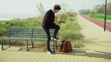 Sırt çantasından notlar alan ve parktaki bankta çalışmaya başlayan adam. . 