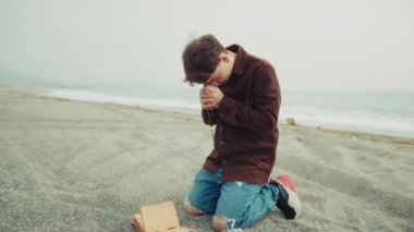 Sadık adam sahilde İncil 'le tutkuyla dua ediyor. . 