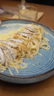 Garson, akşam yemeği masasına yanında Ançüez Tabağı ile spagetti getiriyor.. 