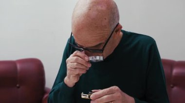 Büyüteçle Çip Bileşenini İnceleyen Adam.