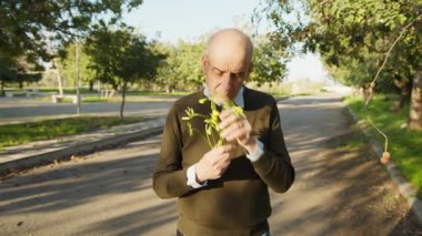 Sarı çiçekleri tutan adam kokularının tadını çıkartır..