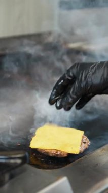 Şef ızgaranın üstüne çedar koyuyor. . 