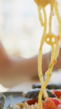 Deniz ürünleriyle spagetti toplamak için çatal kullanan bir kadın. . 