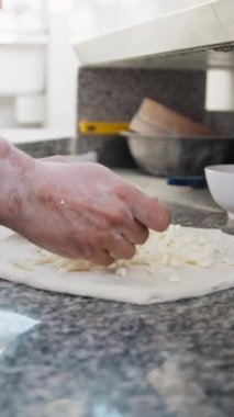 Şef çiğ pizza hamurunun üstüne Mozzarella koyuyor. . 