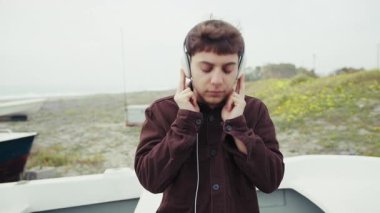 Kışın kıyıda müzik dinleyen bir adam..