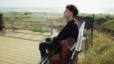 Sahildeki adam deniz kenarında dinleniyor ve doğanın tadını çıkarıyor. . 