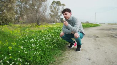 Adam sonbaharda otlardan beyaz bir çiçek topluyor ve ona bakıyor. .