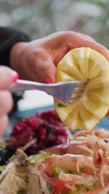 Sahilde öğle yemeğinde çatalla limon sıkan bir kadın. . 