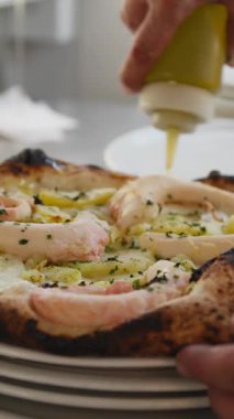 Şef, sıcak ahtapot pizzasının üstüne son parça yağ koyuyor. . 