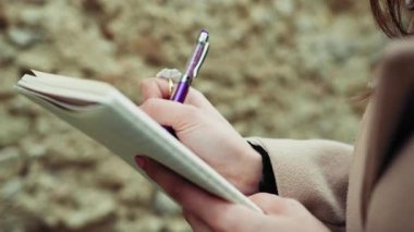 Kağıdın üzerinde Mor Kalemle Kadın Elleri Yakın plan. 