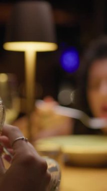 Bir arkadaşla yemek yerken kadehte şarap içen bir kadın. . 