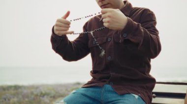 Sahilde dua ederken elinde bir tespih tutan adam. .