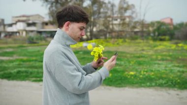 Bir adam, sevdiği kişiye çiçekleri gösterirken, dışarıda bir video görüşmesi yapıyor. .