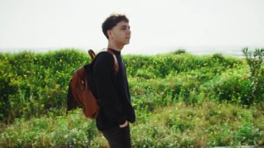 Sırt çantalı bir adam otların yanında doğa yürüyüşü yapıyor.. 