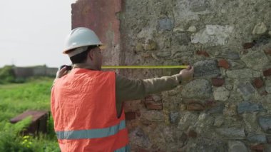 Dışarıdaki eski bina üzerinde Ölçüm Yapan İnşaatçı . 