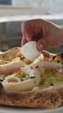 Şef Mozzarella 'yı Ahtapot Ahtapot PIzza' nın üstüne koyuyor.