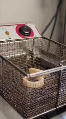 Şef, profesyonel fritözün içine mürekkep balığı halkaları koyuyor. . 