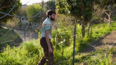 Kırsalda, güneşin altında elinde sepetle yürüyen bir adam.. 