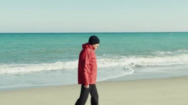 Ceketli Yaşlı Adam Deniz kenarında sakince yürüyor..