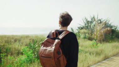 Sırt çantalı bir adam eve dönüyor ve deniz kenarında yürüyor.. 