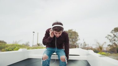 Sahilde bir teknede müzik dinleyen adam . 