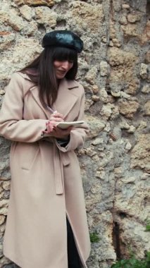 Kadın, şehir sokaklarında defterine bir şeyler yazarken eğleniyor. . 