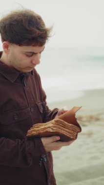 Adam İncil okuyor ve sahildeki sayfaları çeviriyor. . 