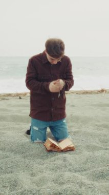 Sahilde İncil 'le dua eden adam .