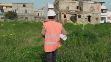 İnşaat alanına varan çimlerin üzerinde yürüyen mimar. . 