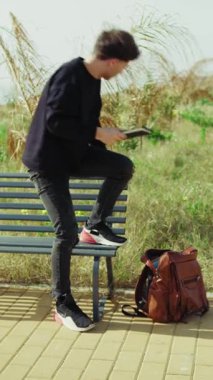 Sırt çantasından notlar alan ve parktaki bankta çalışmaya başlayan adam. . 