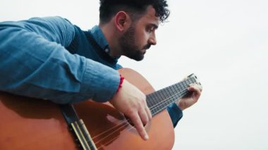Adam açık havada gitar çalarken Arpeggio çalışıyor..