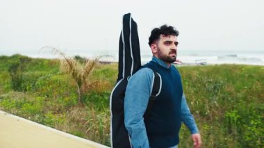 Gitarist sırtında gitarla bisiklet yolunda yürüyor.. 