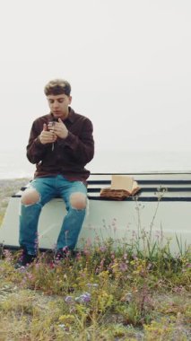 Adam kışın sahilde bir teknede oturur ve dua eder. .