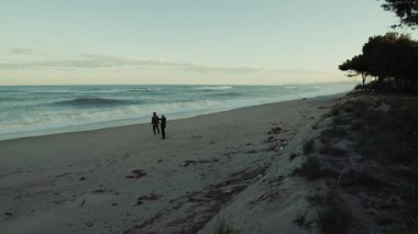 Issız bir plajda Fırtınalı Okyanus Dalgaları sırasında İki Adam Rahatlamak İçin Yürür.