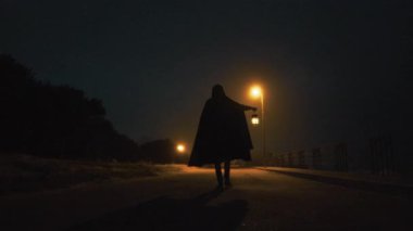 Karanlık bir sokakta yürüyen gizemli bir adam Cadılar Bayramı hayalet gecesinde.