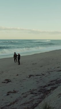 Issız bir plajda Fırtınalı Okyanus Dalgaları sırasında İki Adam Rahatlamak İçin Yürür.