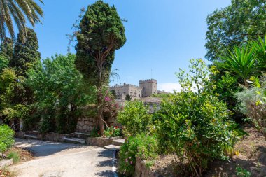 Rodos şövalyelerinin büyük ustasının sarayını gösteren bir resim. Şato arka planda ağaçlar ve çiçeklerle birlikte ön planda görülebilir..