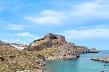 Rodos adasındaki eski Lindos tiyatrosu. St Paul Körfezi, arka planda deniz olan ön planda yer alır.