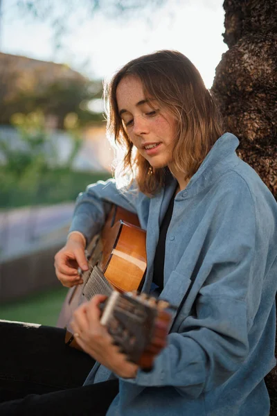 Усміхнена Дівчина Грає Гітарі Спираючись Дерево Парку — стокове фото