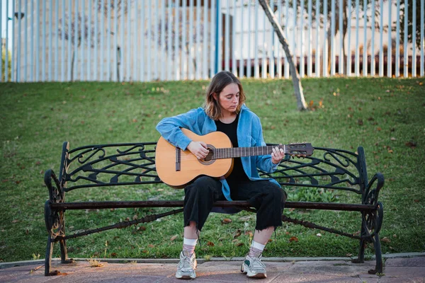 Adolescente Parece Concentrar Tocando Guitarra Enquanto Sentado Banco Parque — Fotografia de Stock