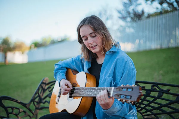 Menina Sorridente Tocando Guitarra Enquanto Ela Está Sentada Banco Parque — Fotografia de Stock