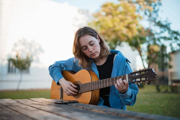 Jovem Mulher Compondo Uma Música Com Sua Guitarra Enquanto Senta — Fotografia de Stock